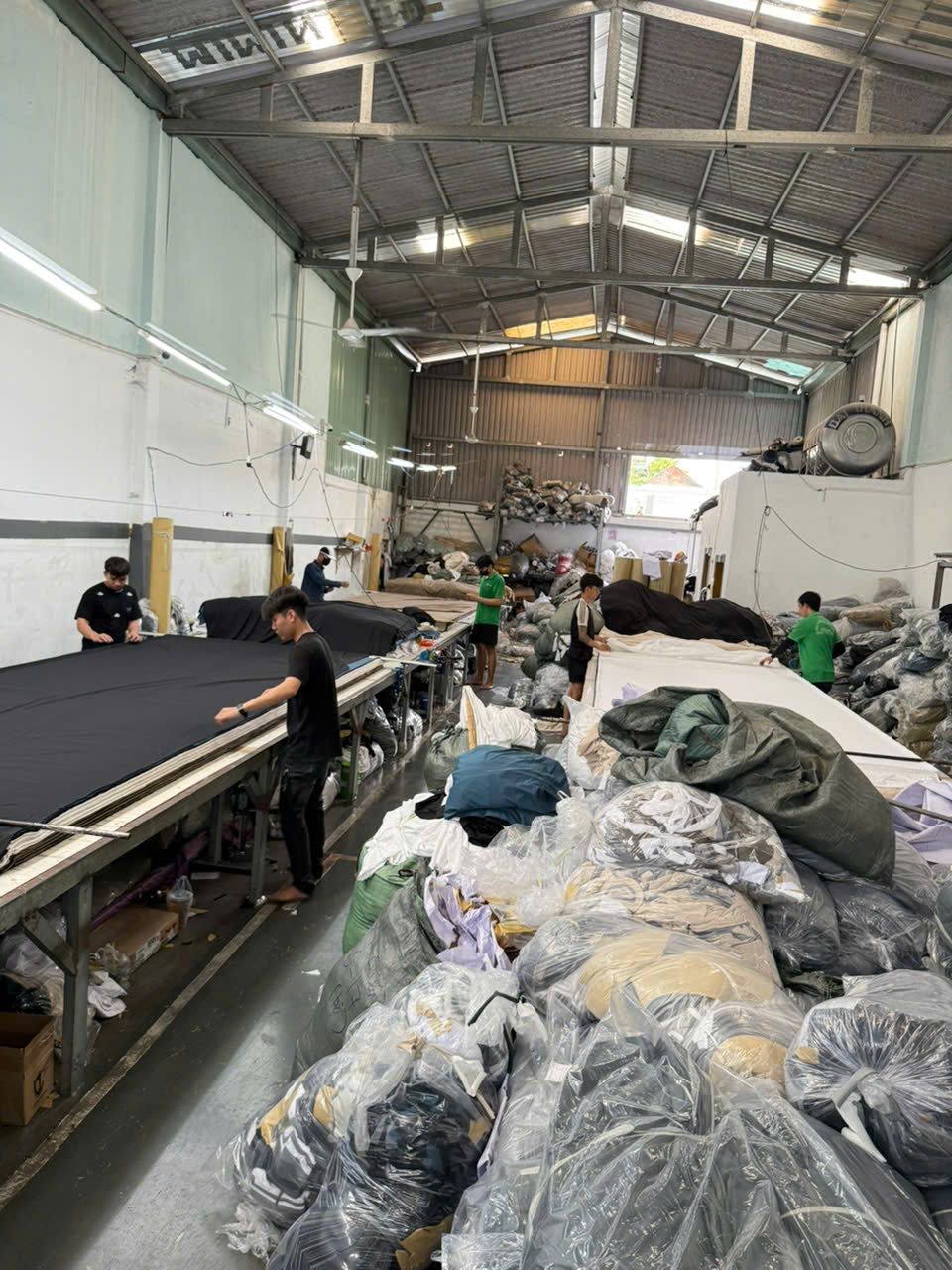 Nhà xưởng may POLOMIMIN, thợ đang trải vải trên bàn cắt